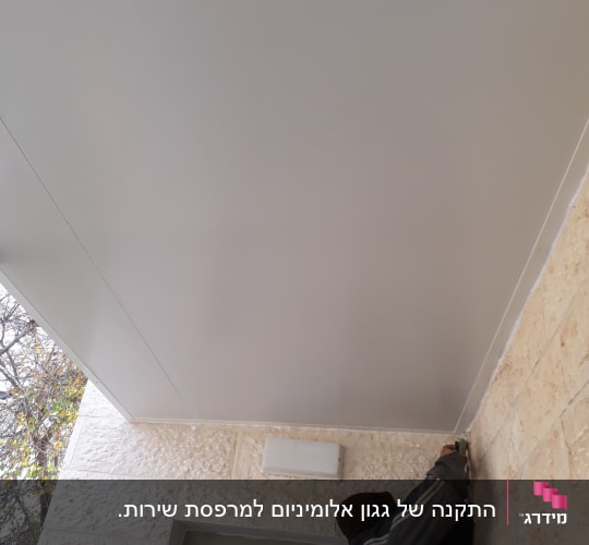 אדם מתקין תקרה מאלומיניום עם כלי עבודה
